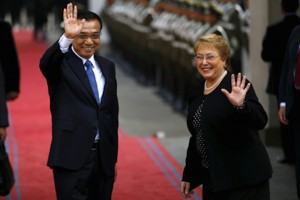 Chinese Premier Li Keqiang and Chile's President Michelle Bachelet wave to the media at the government palace in Santiago city