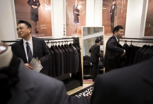 Booth attendants stand in front of formal suit jackets displayed at the Life Ending Industry Expo in Tokyo, Japan, on Tuesday, Dec. 8, 2015. The exhibition of equipment, products and services for funeral, burial and memorial services runs through Dec. 10. Photographer: Tomohiro Ohsumi/Bloomberg